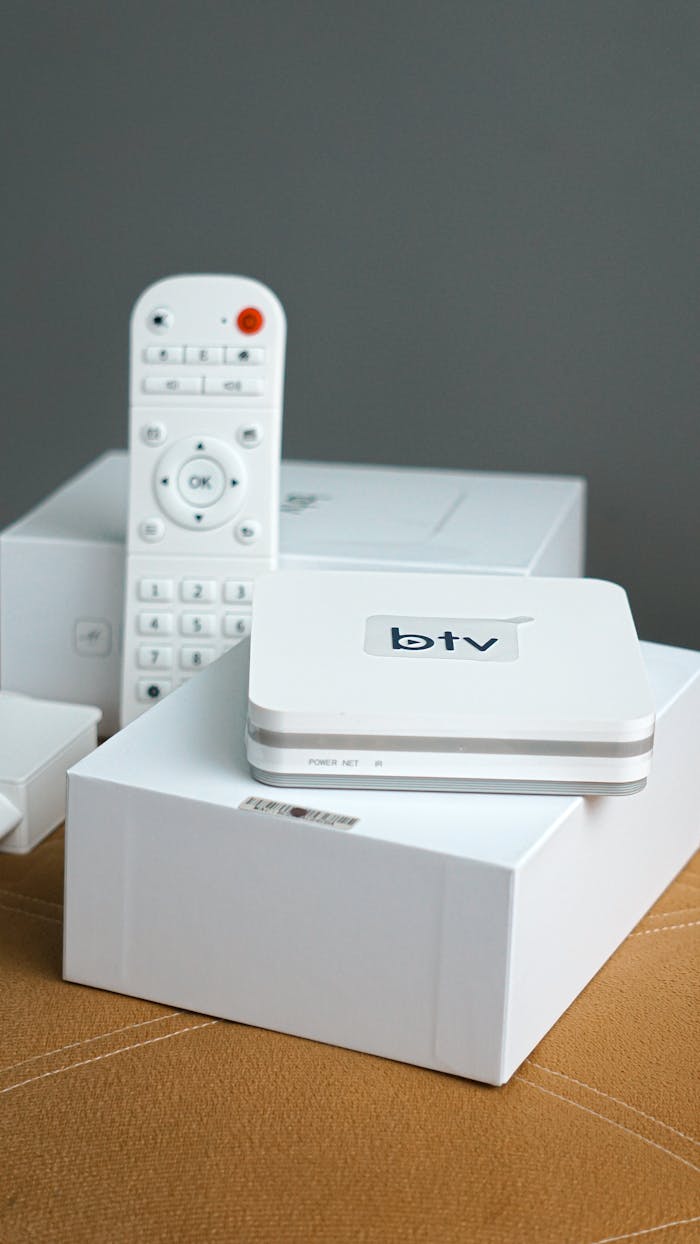 Vertical shot of a modern smart TV setup including a remote control and electronic device.
